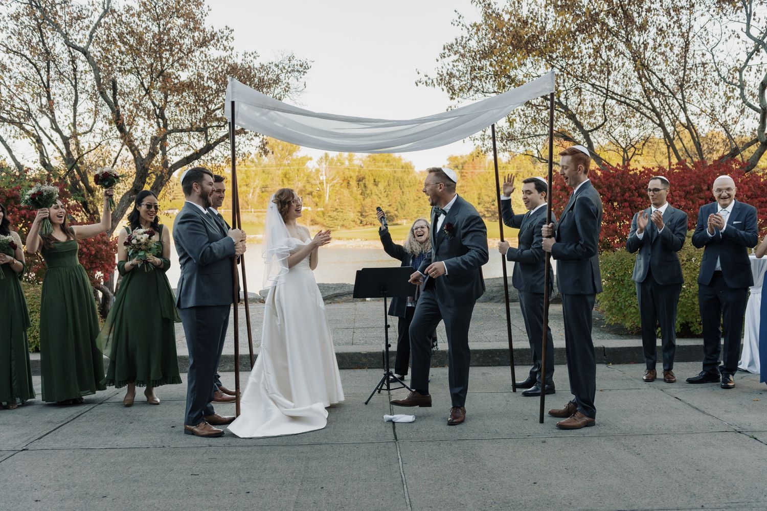 Bride and groom under a white tent at The Manor in King City during their Jewish wedding ceremony with wedding party.