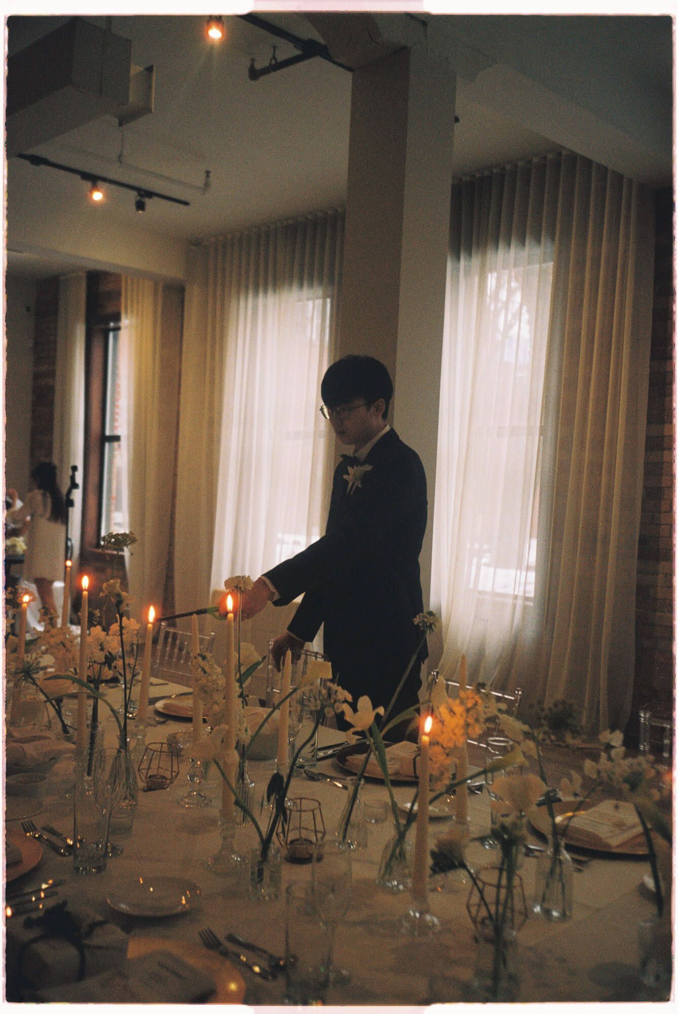 Person lighting candles on a floral reception table at Archive Studio in Toronto for intimate 35mm film wedding photography.