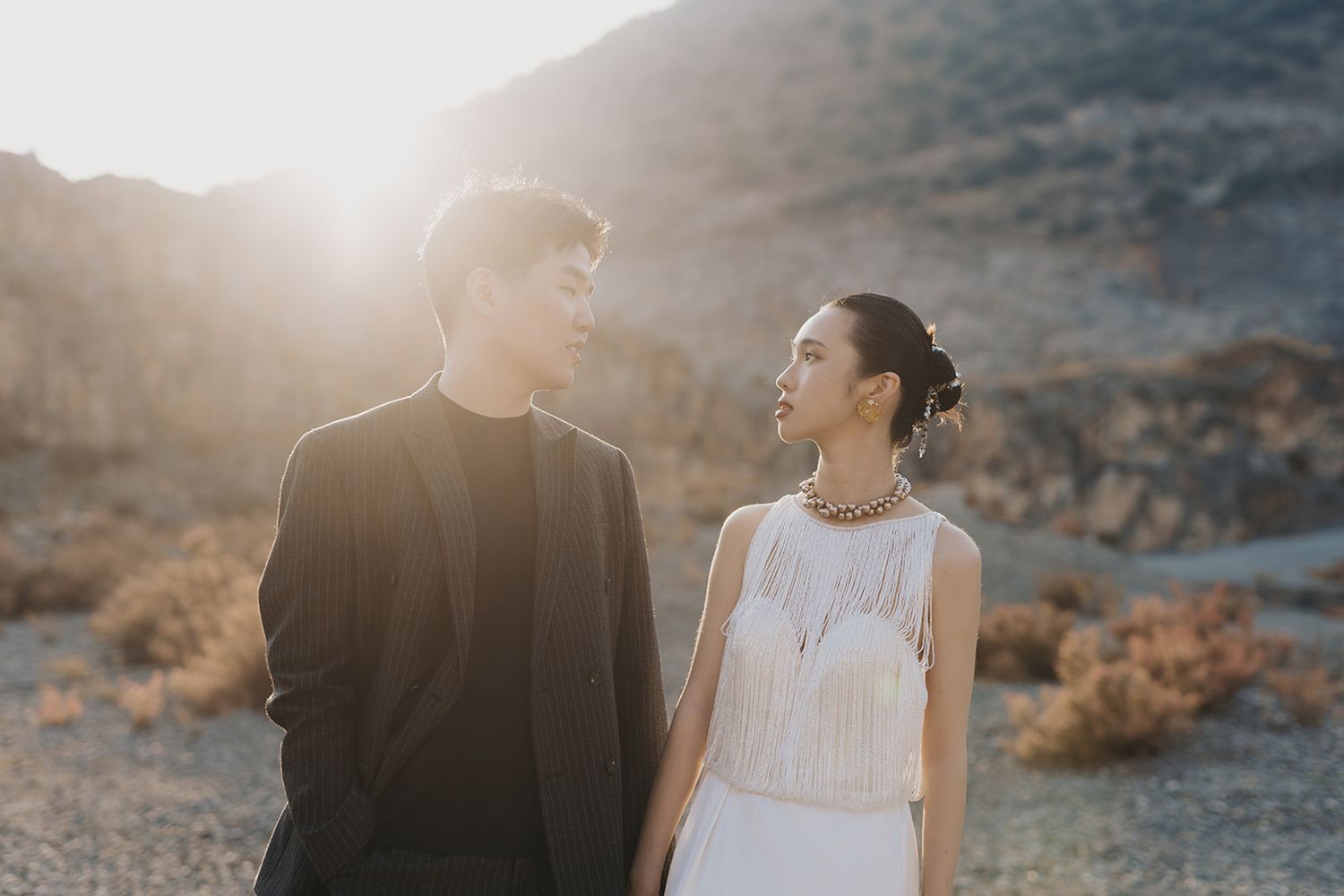 Couple sharing a romantic golden hour moment in a sunlit desert during an editorial destination wedding portrait session