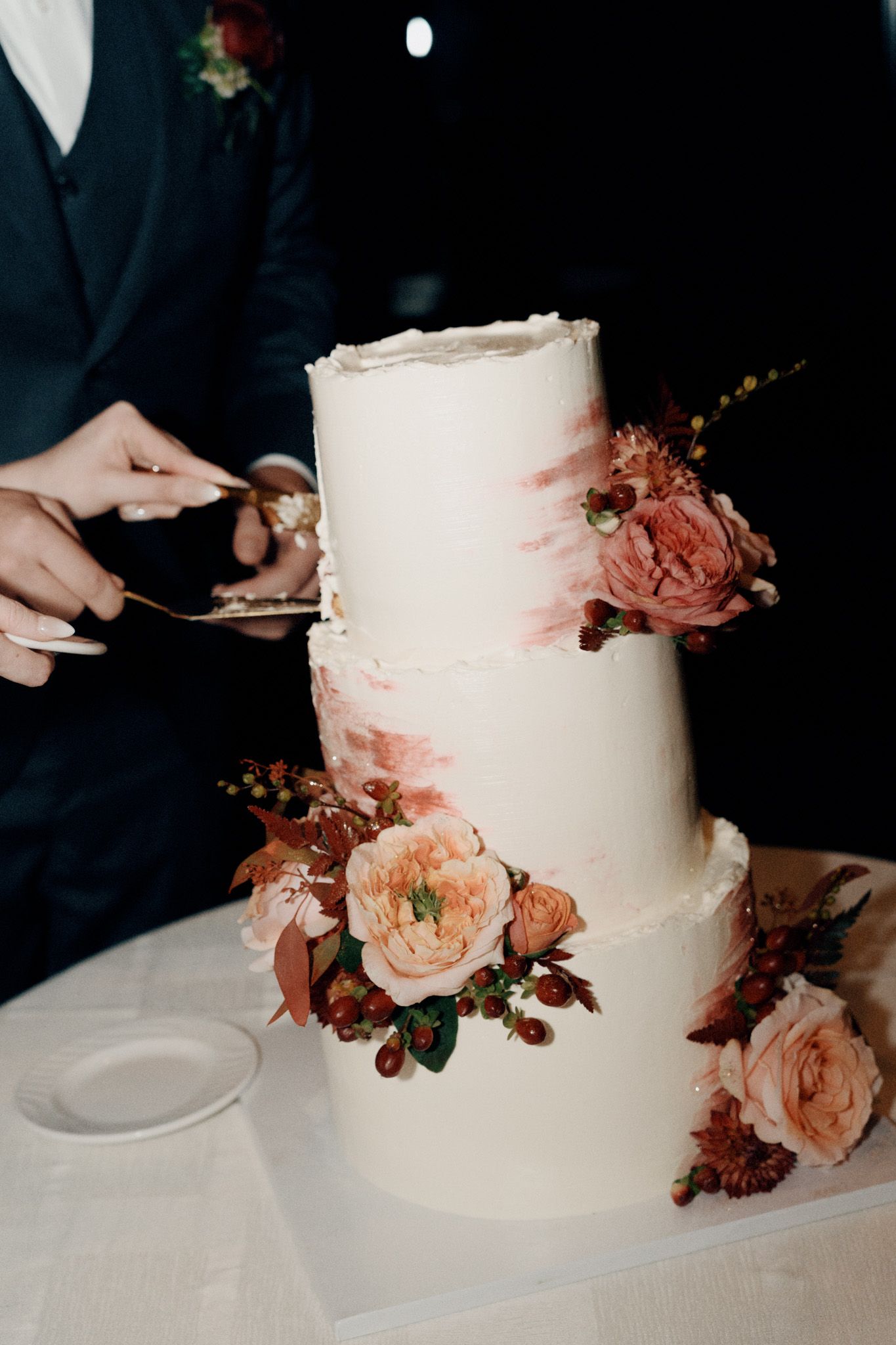 Bride and groom cutting a three-tier floral wedding cake at The Manor in King City during their Jewish wedding reception.