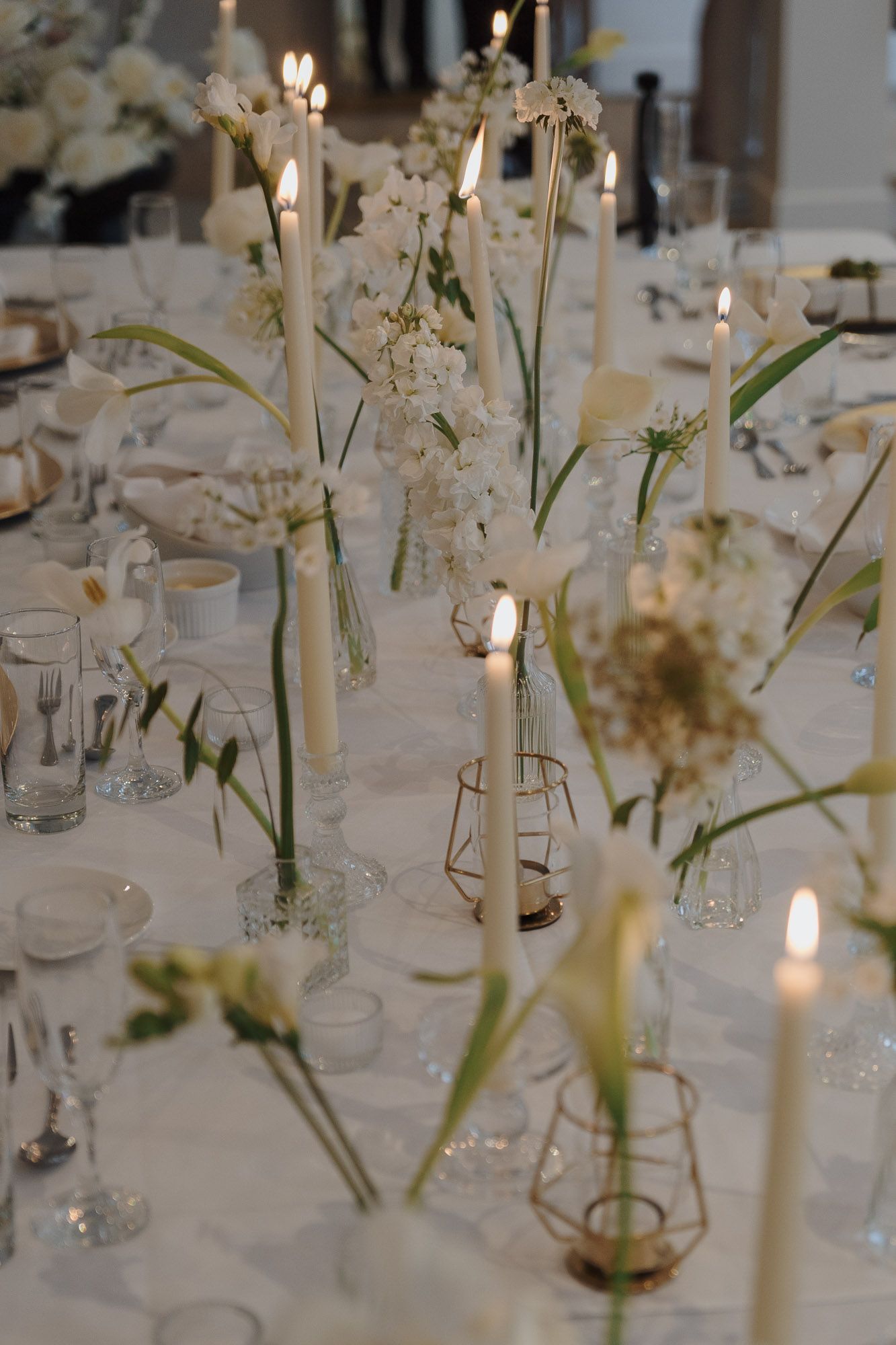 White taper candles, delicate florals, and gold candle holders on a table at Archive Studio in Toronto for intimate wedding photography.