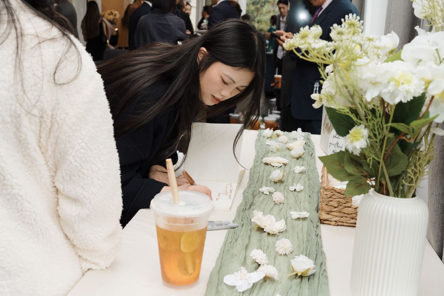 Guest writing at a white floral reception table with bubble tea during a Razi Estate forest wedding, Schomberg, ON Toronto Photography
