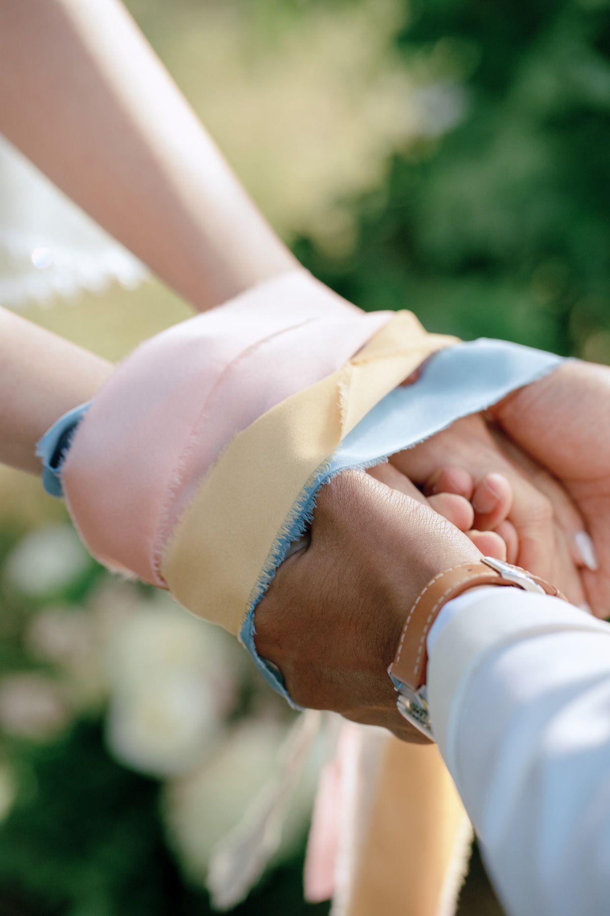 Couple’s hands bound with pastel ribbons during a handfasting ceremony at Kurtz Orchards in Niagara-on-the-Lake wedding.