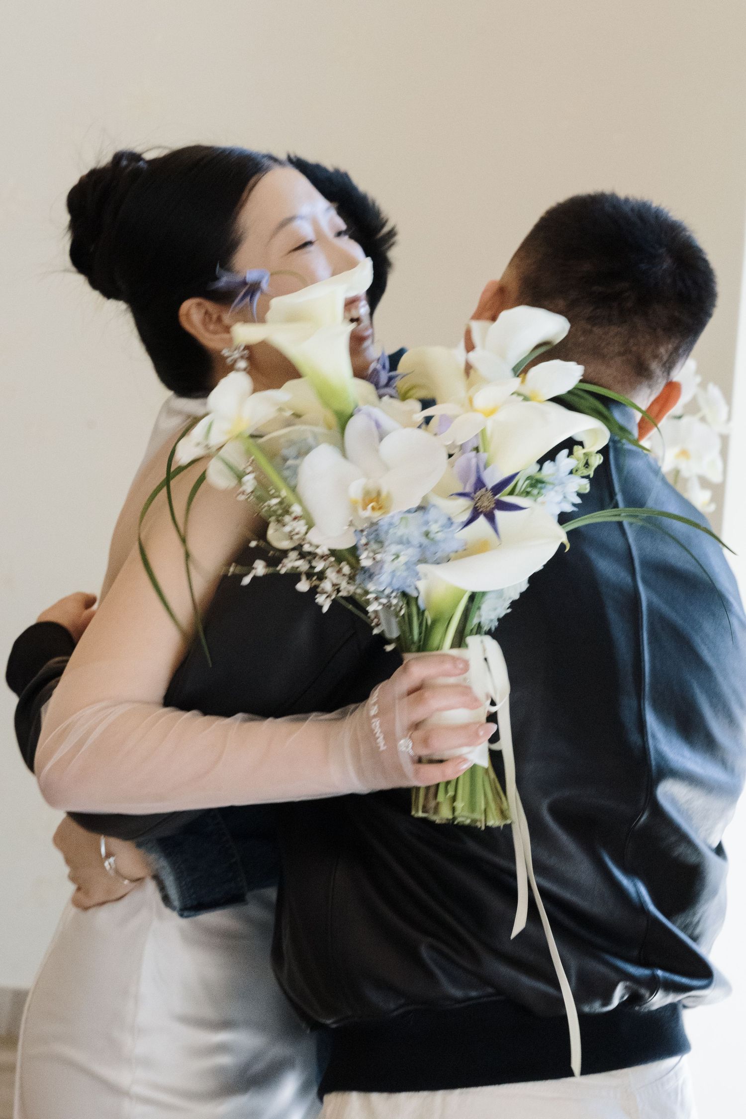 Bride and groom embracing with calla lilies and blue bouquet during an emotional downtown Toronto City Hall ceremony.