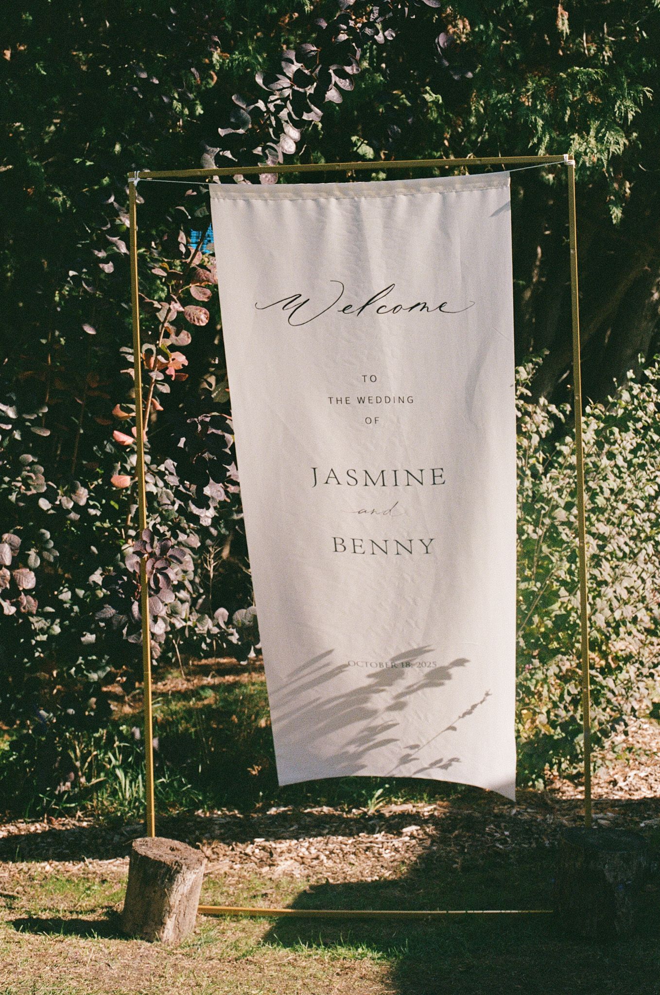 Fabric wedding welcome sign for Jasmine and Benny on a gold stand at Razi Estate in Schomberg for forest wedding photography.
