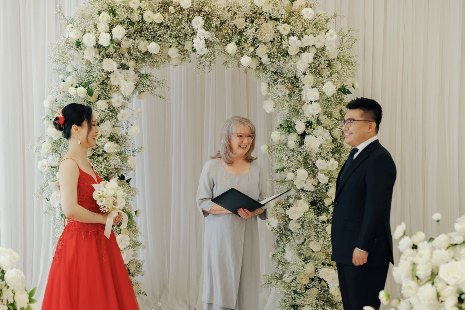 Couple exchanging vows beneath a white floral arch at Bellamy Loft in North York, Toronto for elegant wedding photography.