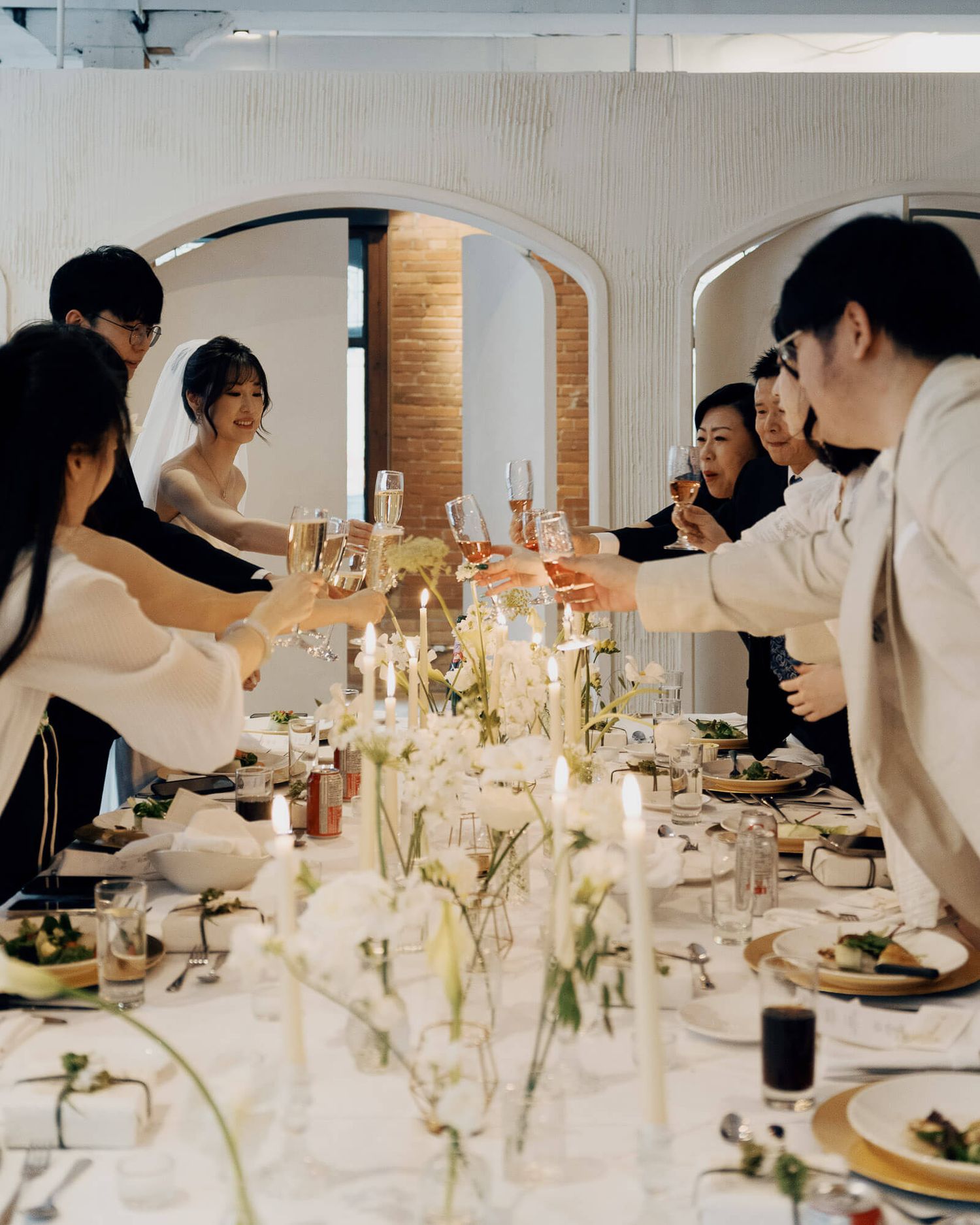 Guests raising champagne glasses around white floral centerpieces at Archive Studio in Toronto for intimate wedding reception photography.