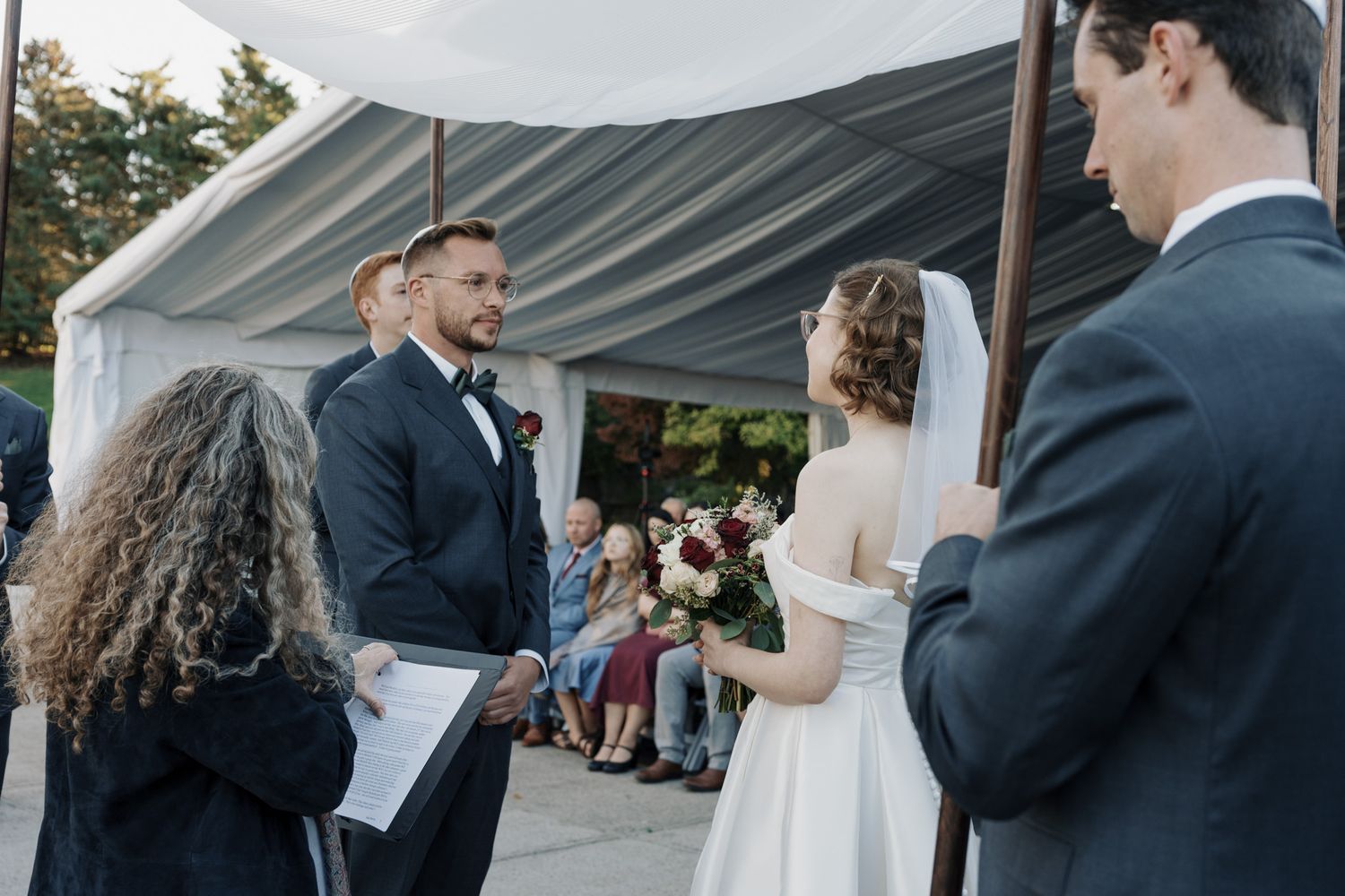 Bride and groom exchanging vows under a white tent at The Manor in King City during their Jewish wedding ceremony.