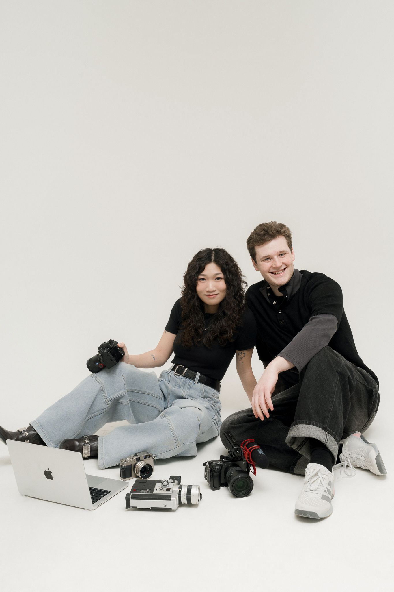 Clarise and Brad, Toronto wedding photographers and videographers behind ILO Studio, with cameras and laptop during a branding shoot.