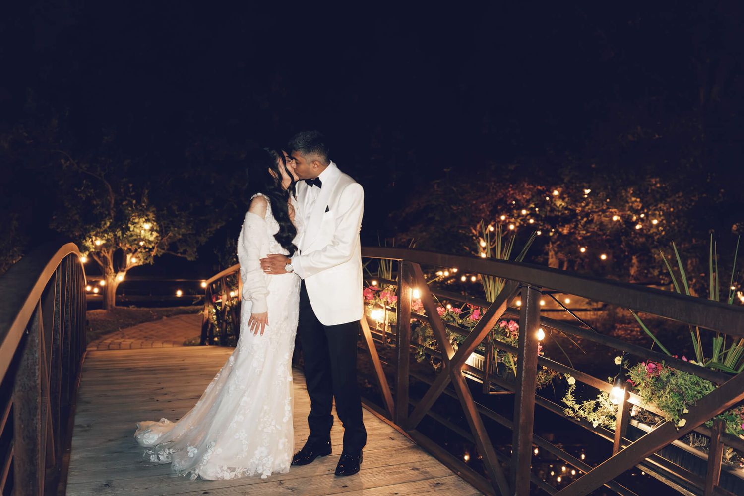 Romantic nighttime wedding photo of a couple kissing on a wooden bridge at Kurtz Orchards in Niagara-on-the-Lake.