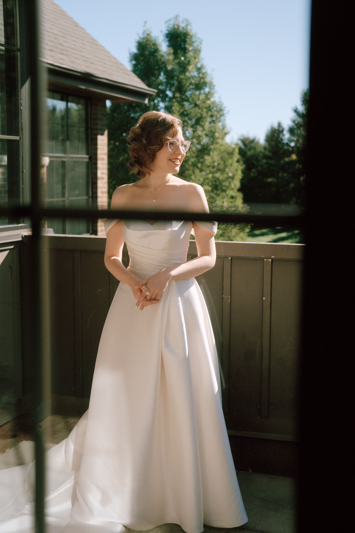 Jewish bride smiling on a sunlit balcony at The Manor in King City for elegant Toronto wedding photography