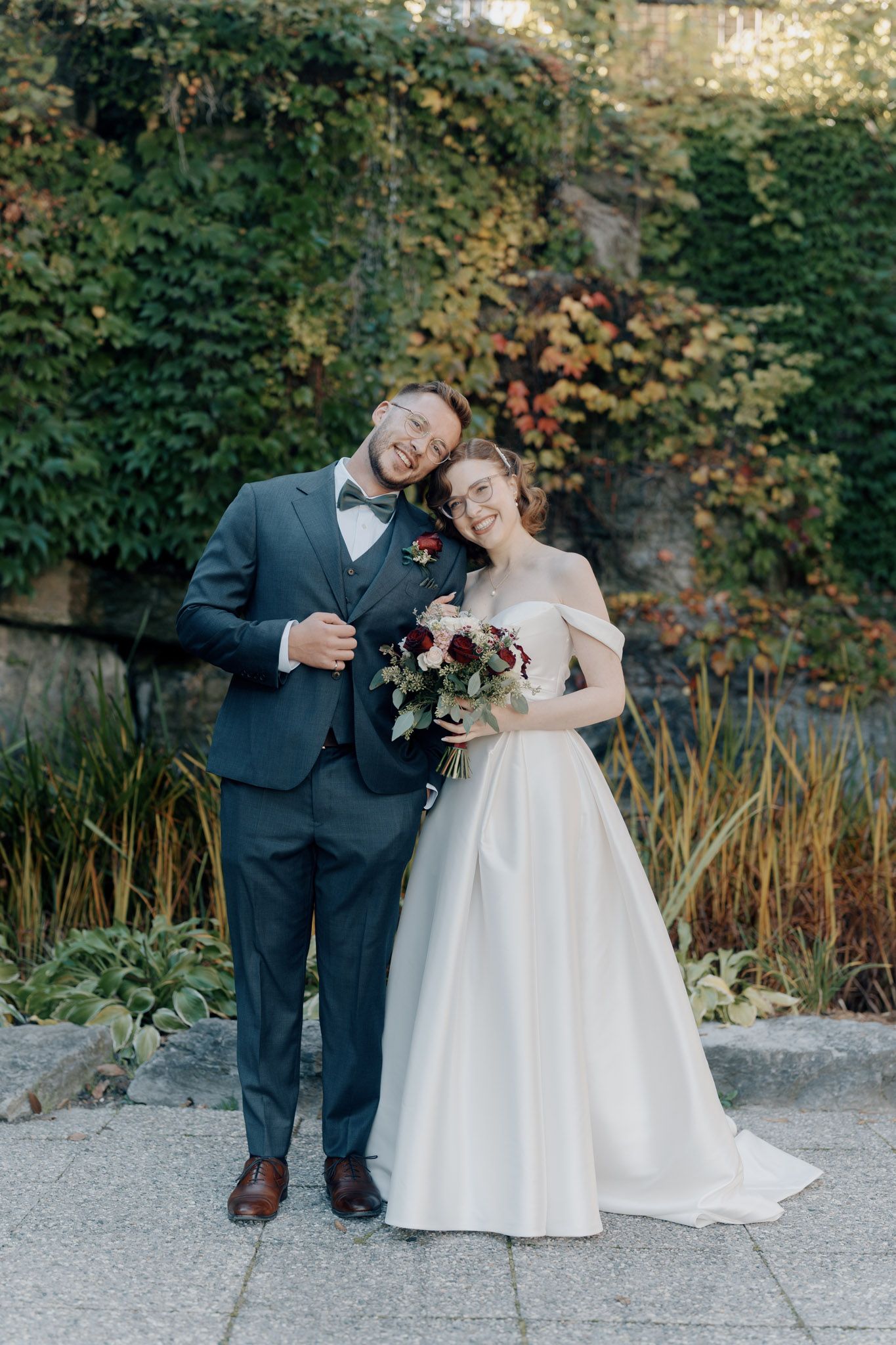 Bride and groom posing with bouquet before ivy-covered walls at The Manor in King City for Toronto wedding photography