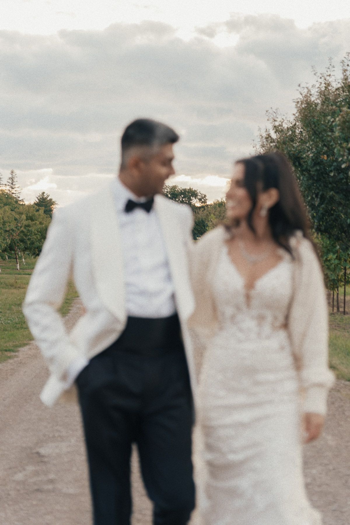 Bride and groom walking through a vineyard path at sunset at Kurtz Orchards in Niagara-on-the-Lake for romantic wedding photography.
