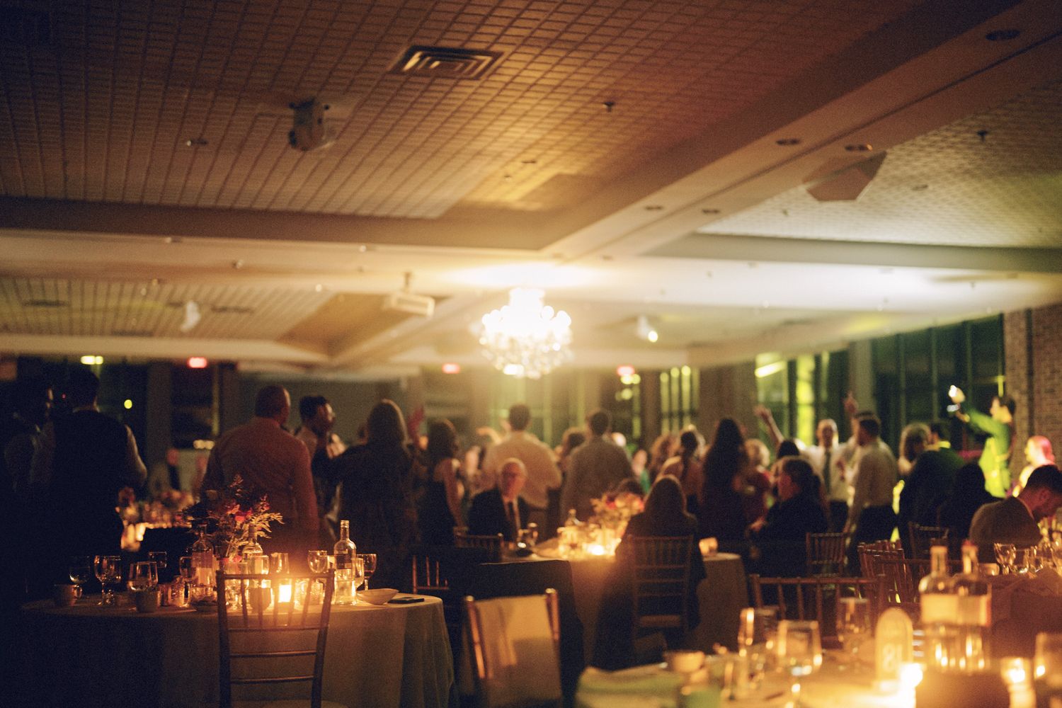 Candlelit Jewish wedding reception with guests dining beneath glowing chandeliers at The Manor in King City.