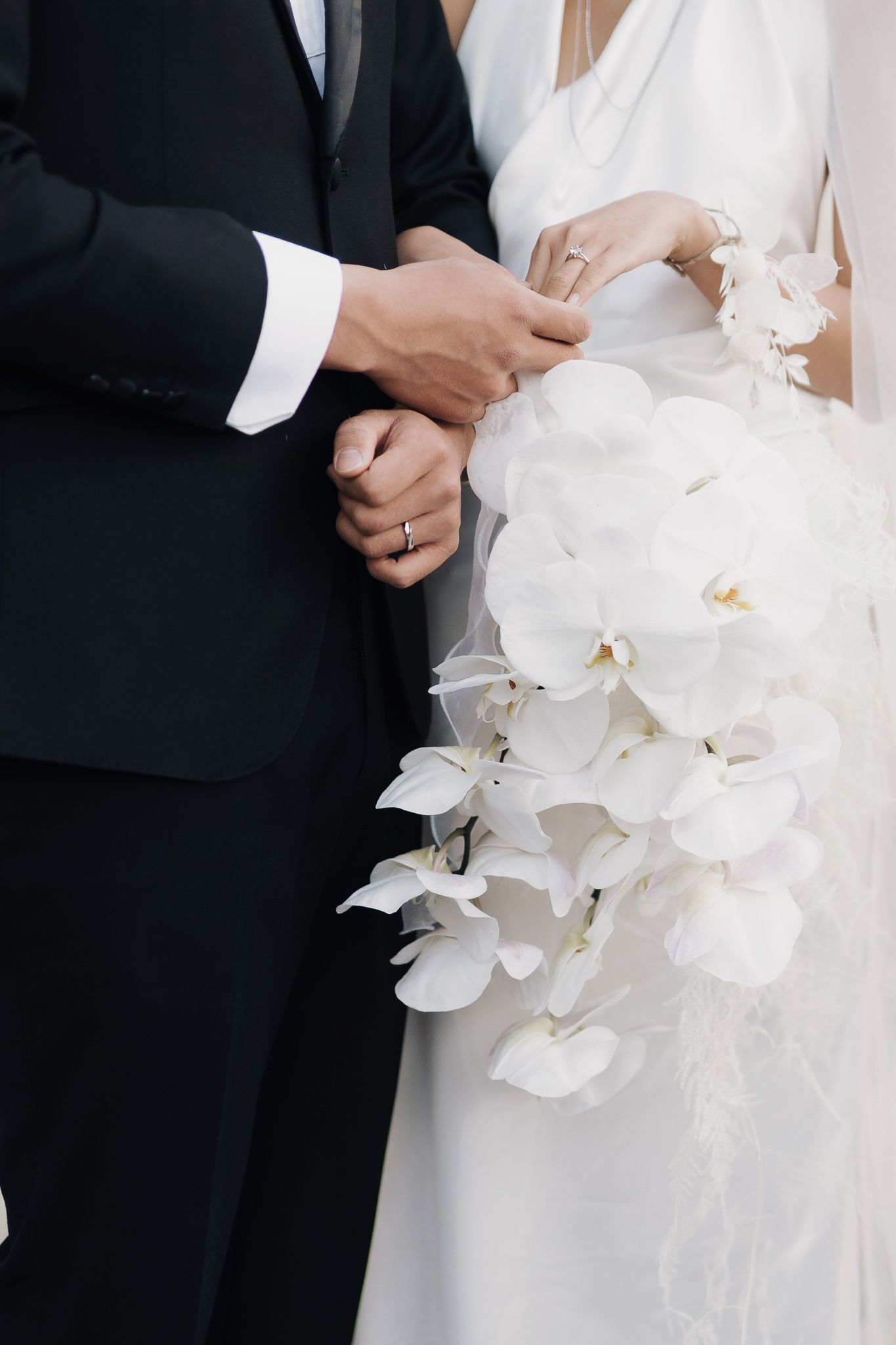 Bride and groom holding hands with a white orchid bouquet during an elegant Toronto luxury wedding portrait session