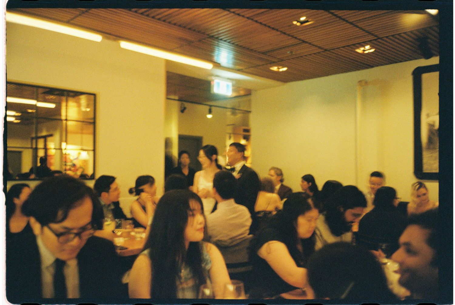 Crowded restaurant dining room filled with guests seated at tables during a lively evening gathering or celebration.