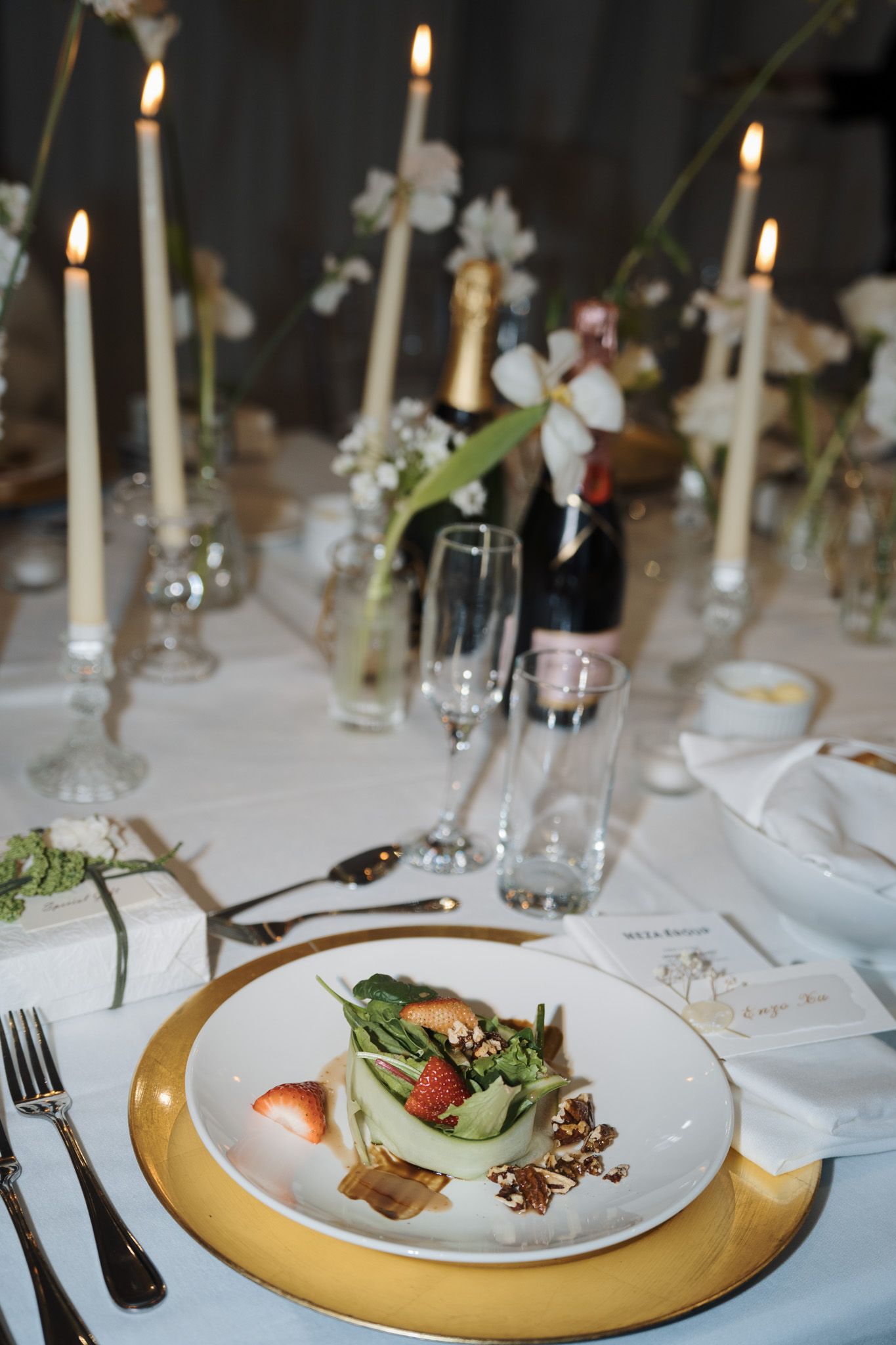 Elegant wedding table setting with candles, champagne, florals, and plated dessert for a romantic wedding reception.