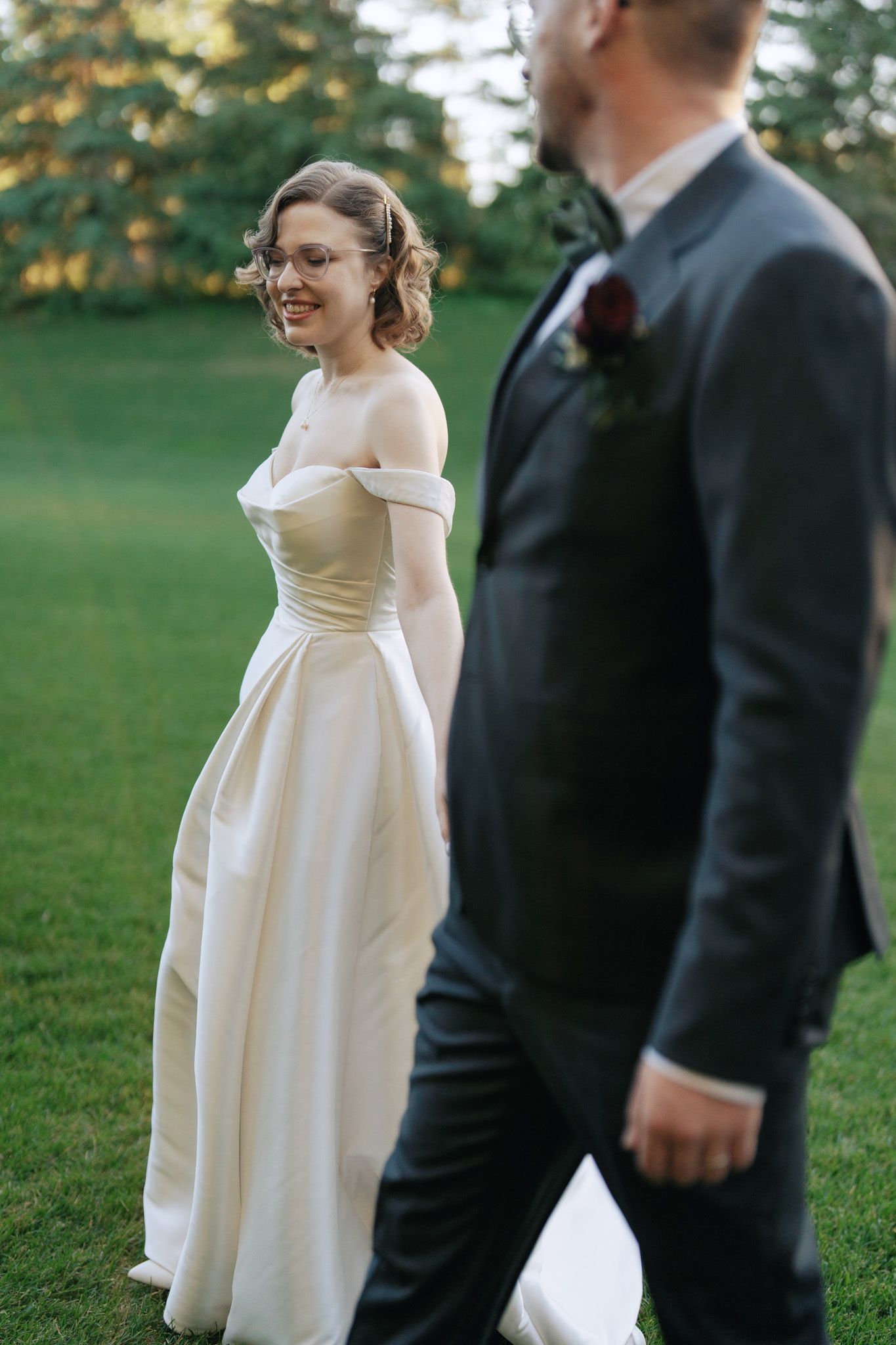 Smiling bride and groom walking on the lawn at The Manor in King City during their outdoor Jewish wedding portraits
