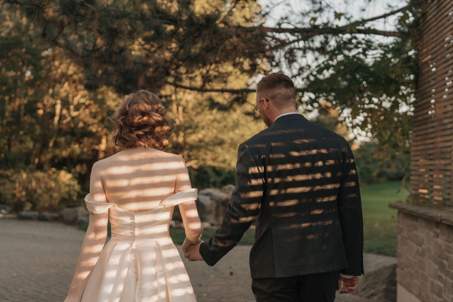 Bride and groom holding hands on a garden path during sunset portraits at The Manor in King City wedding photography