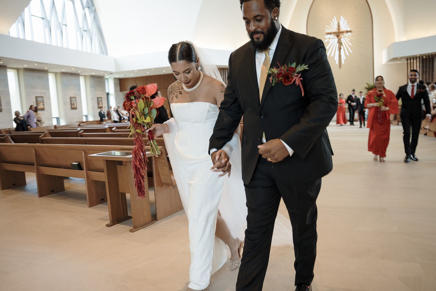 A newlywed couple walks hand in hand down the church aisle after their wedding ceremony.