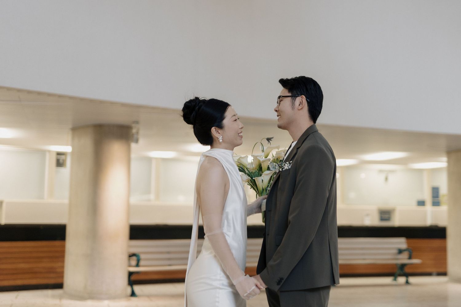 Couple holding hands during a first-look reaction at an intimate Toronto City Hall wedding with elegant columns.