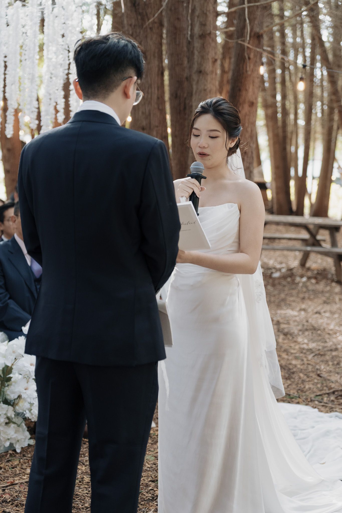 Bride reading vows to groom during an outdoor forest wedding ceremony at Razi Estate in Schomberg, Ontario.