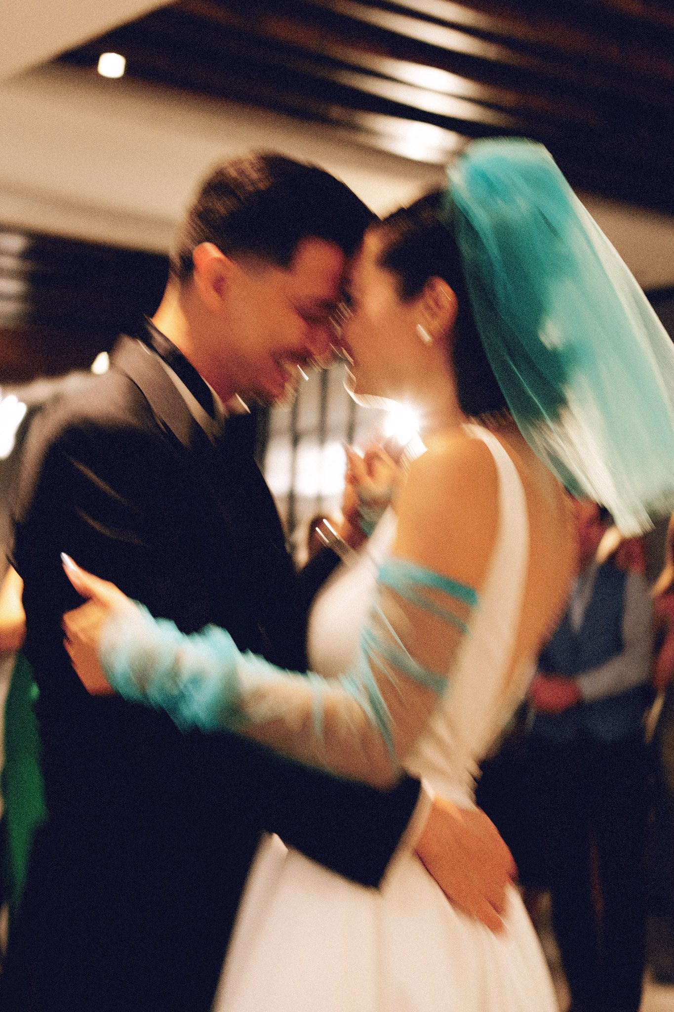 Bride wearing teal veil and groom sharing an intimate first dance at wedding reception.