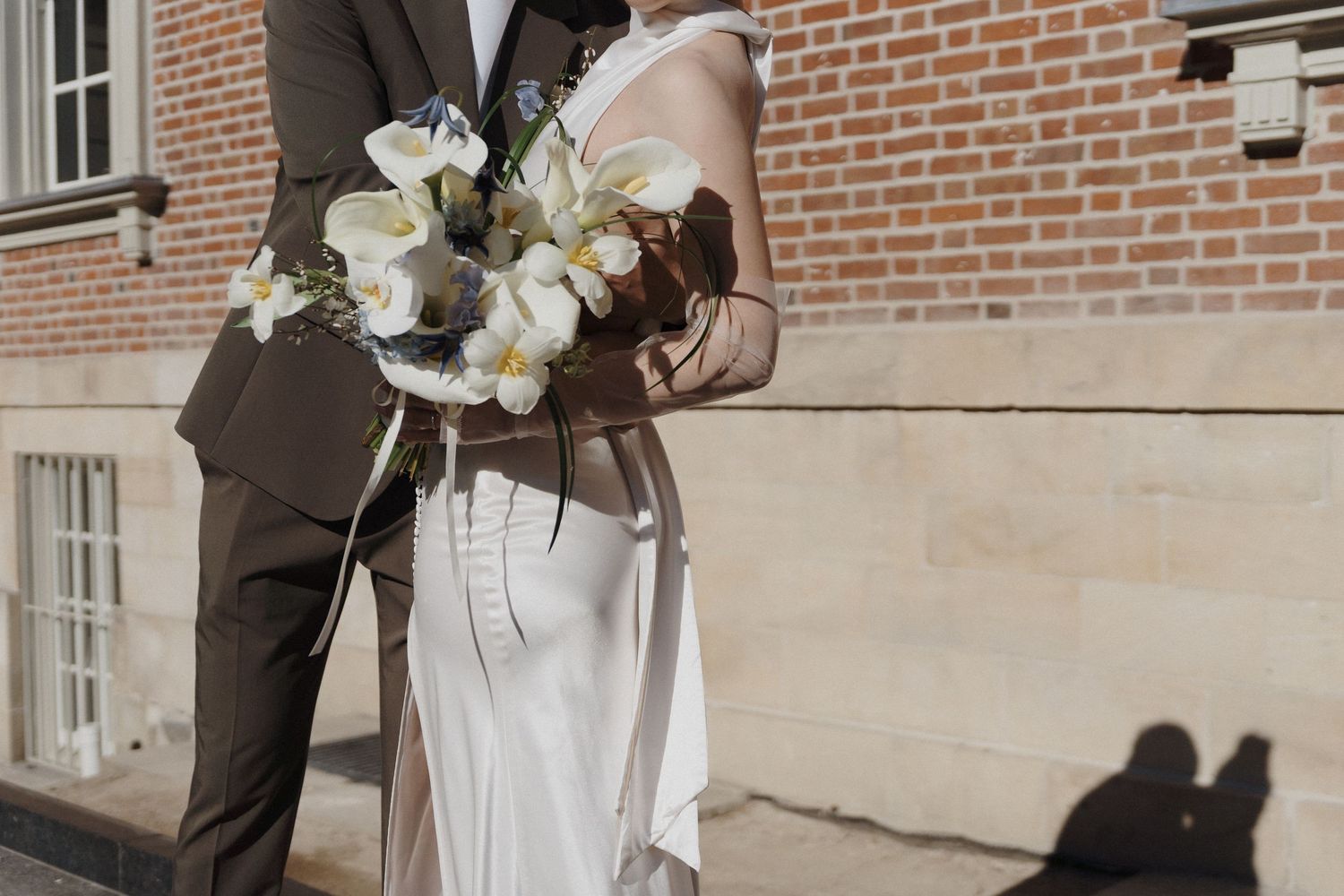 Bride and groom holding a white orchid bouquet during a quiet courtyard moment at Osgoode Hall for Toronto City Hall wedding photography.