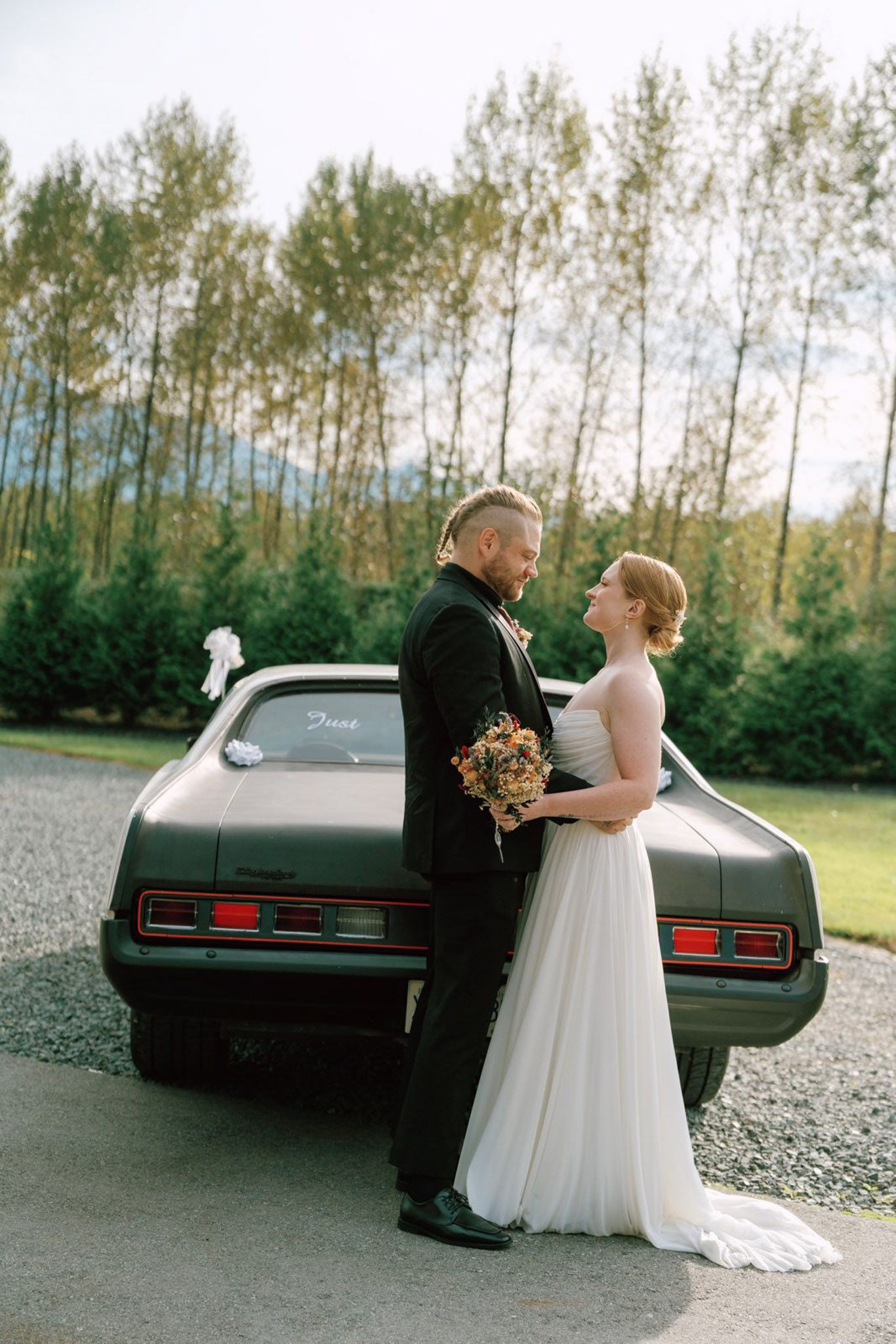 Bride and groom share a romantic moment beside a vintage green car at Bridlewoods Event Center in Chilliwack, B.C. Vancouver