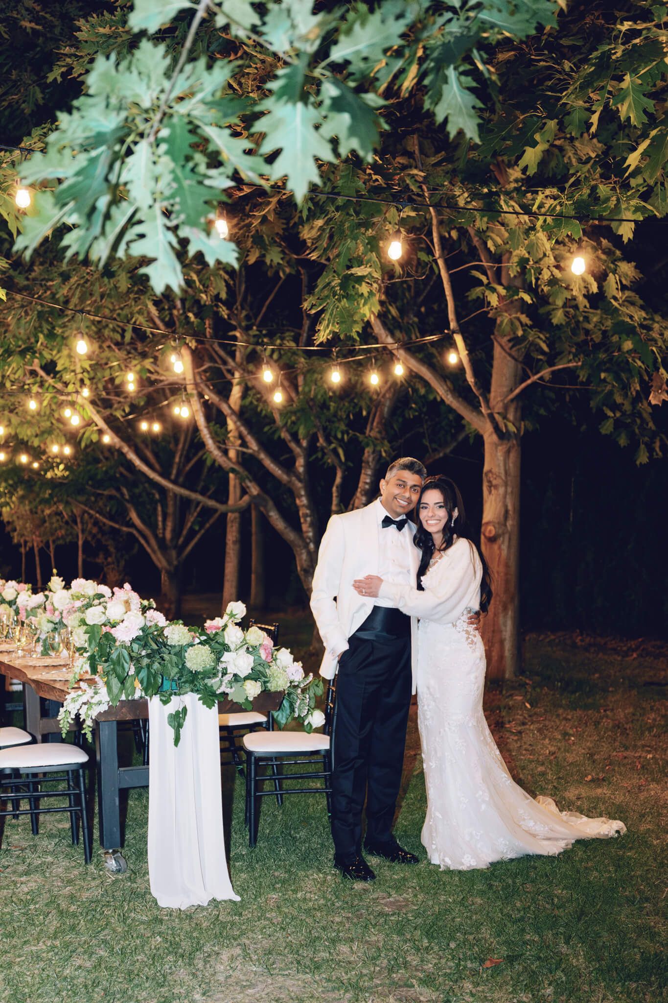 Bride and groom embracing under string lights at Kurtz Orchards in Niagara-on-the-Lake during a romantic outdoor wedding reception.