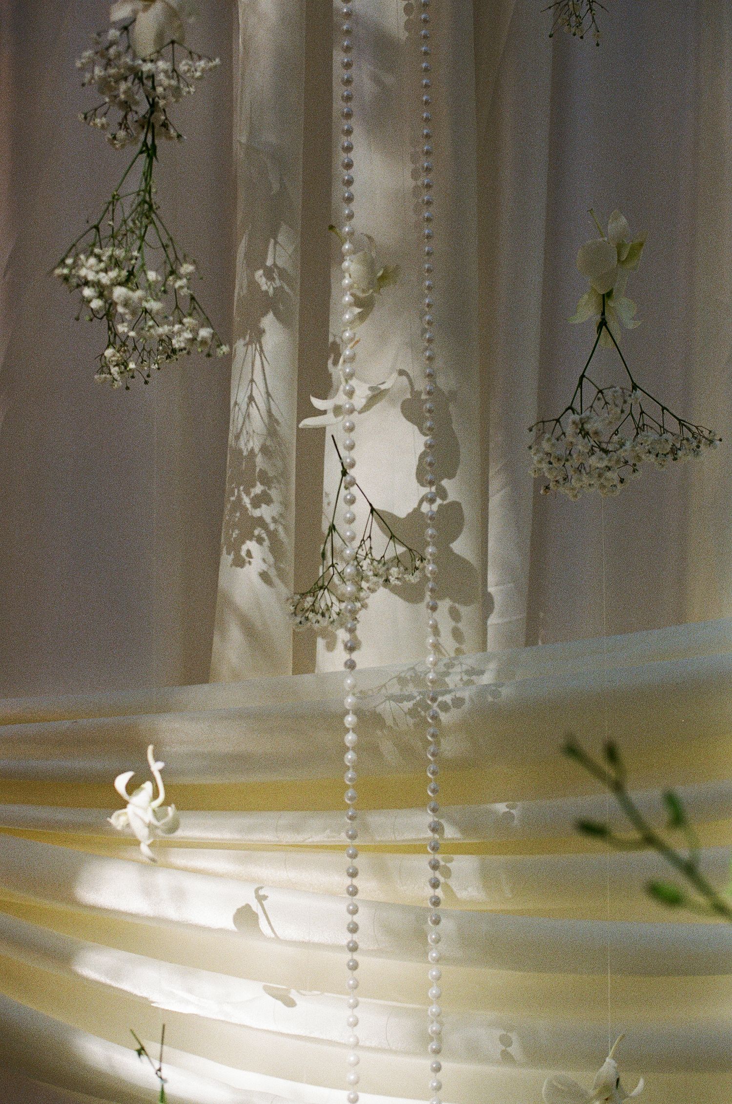 Elegant white wedding reception décor with hanging baby’s breath, pearl strands, and sheer draping at a King City wedding