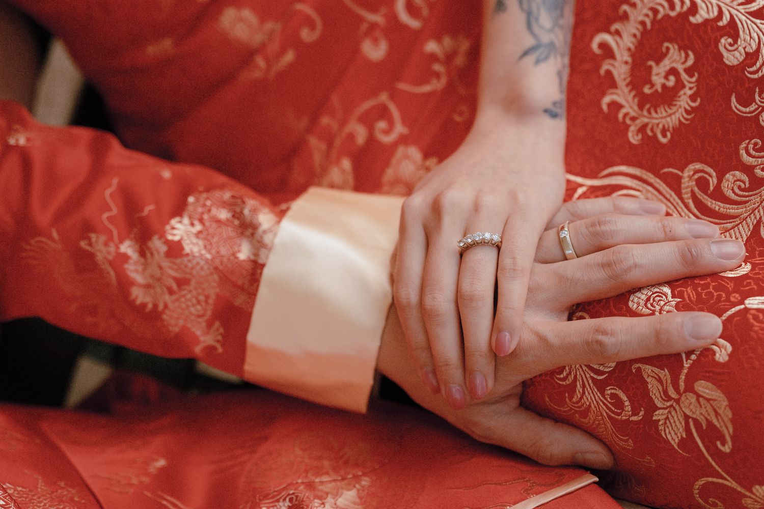 Bride’s hands with diamond ring against a red qipao with gold embroidery during a traditional Chinese tea ceremony in Toronto.