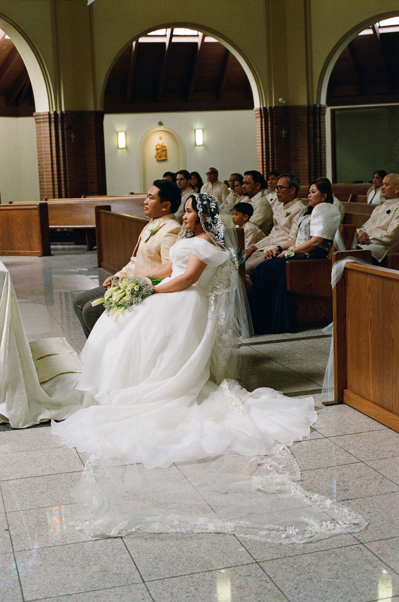Bride and groom seated in church pews during their Catholic ceremony at St. Joseph’s Parish in Langley for Vancouver wedding photography