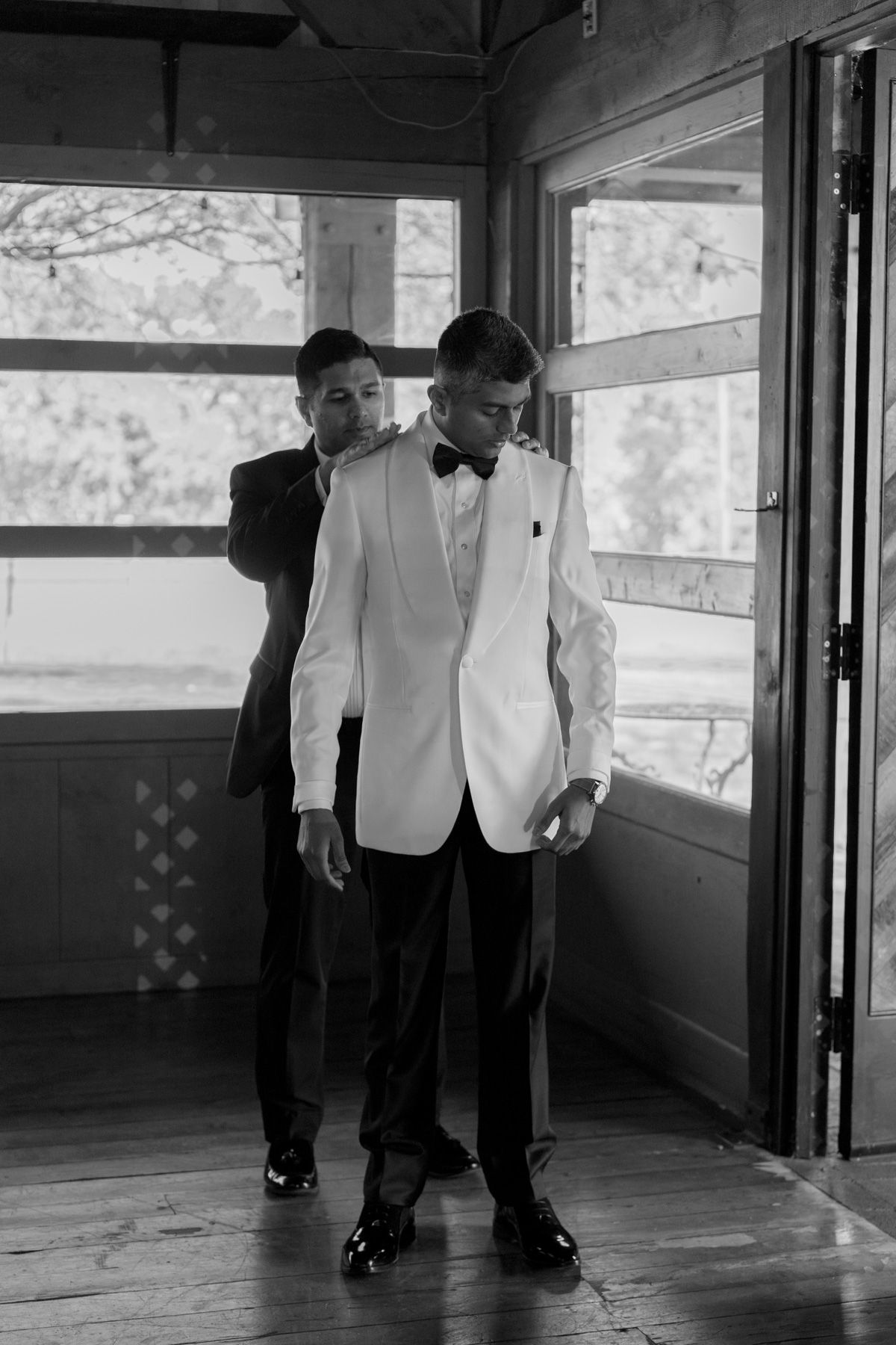 Black and white grooms preparing together in formal attire at Kurtz Orchards in Niagara-on-the-Lake wedding morning.