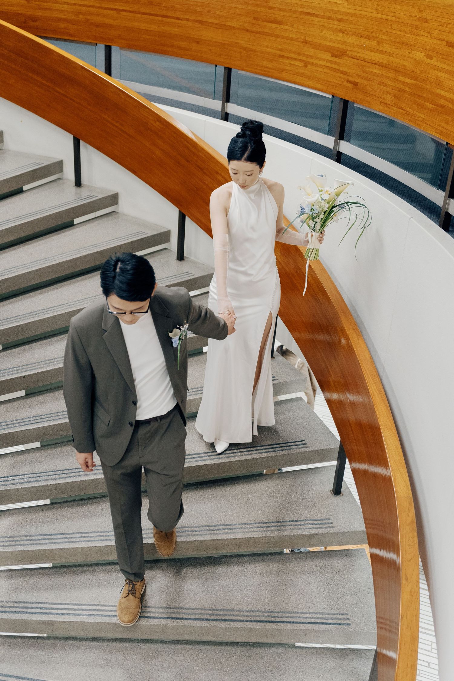 Bride and groom descending a curved wooden staircase at Toronto City Hall for editorial wedding photography.