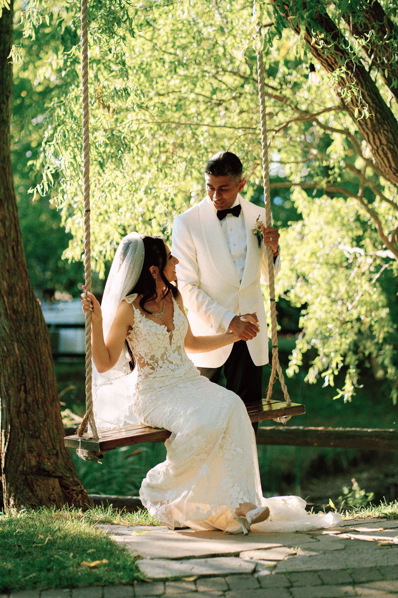 Bride on a wooden tree swing holding the groom’s hand at Kurtz Orchards in Niagara-on-the-Lake, Ontario