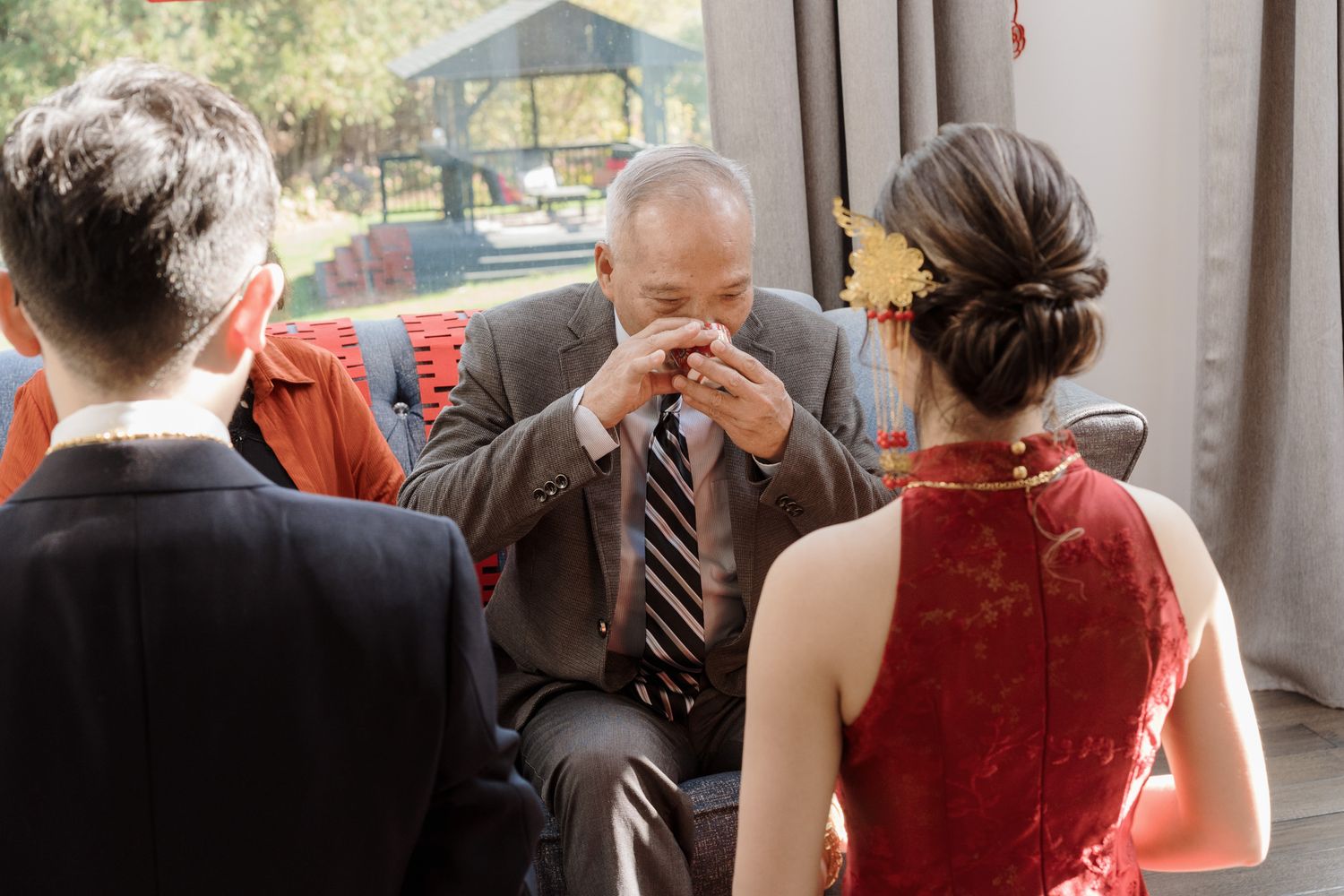 Emotional father wiping tears beside bride in red qipao during Chinese tea ceremony at Razi Estate in Schomberg.