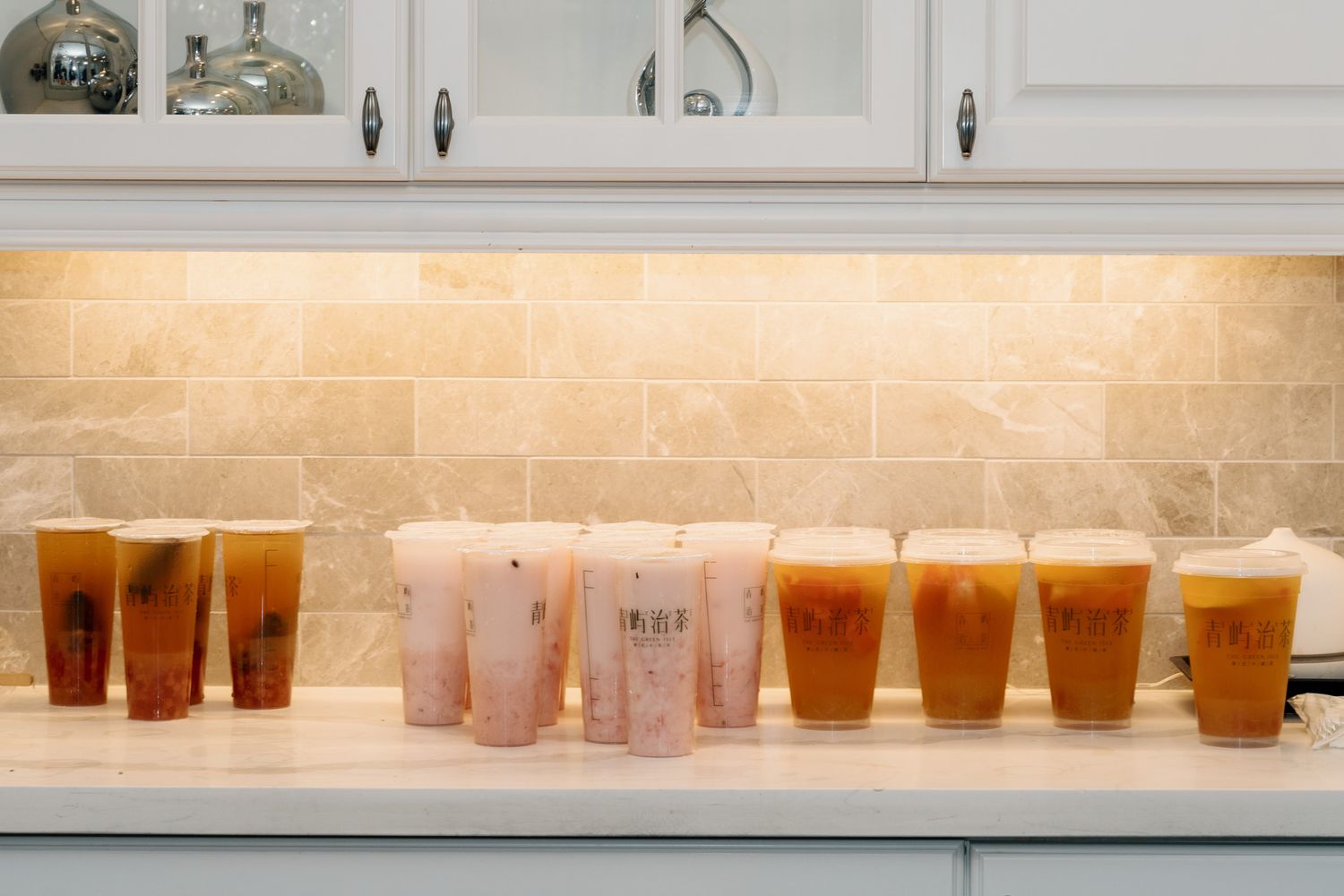 A row of colorful bubble tea drinks with boba pearls lined up on a white marble kitchen counter. Razi Estate forest wedding, Schomberg, ON