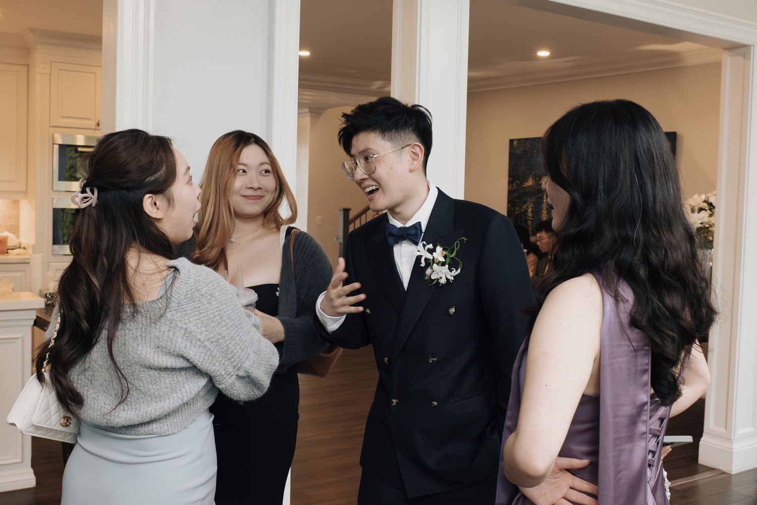 Groom in black tuxedo laughing with guests during an elegant indoor reception at Razi Estate forest wedding, Schomberg, ON