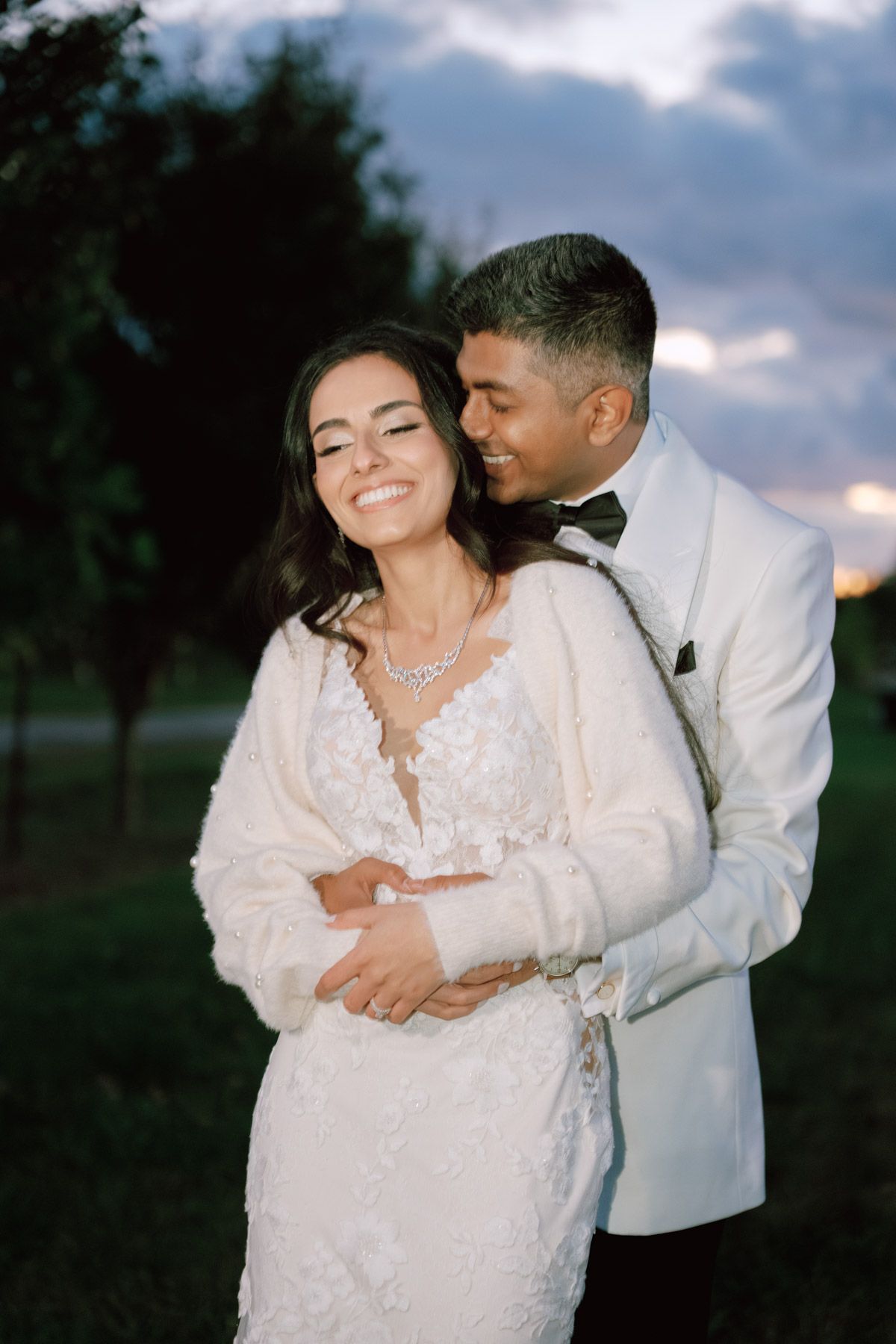 Bride and groom embracing at sunset in white wedding attire at Kurtz Orchards in Niagara-on-the-Lake for romantic wedding photography.
