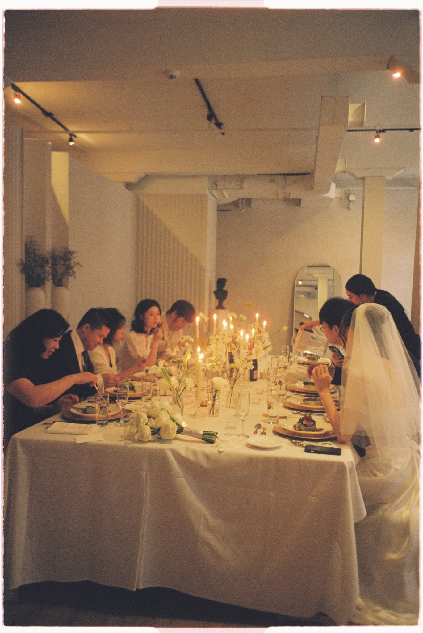 Bride in veil joining guests at a candlelit reception dinner at Archive Studio in Toronto for candid Toronto wedding photography
