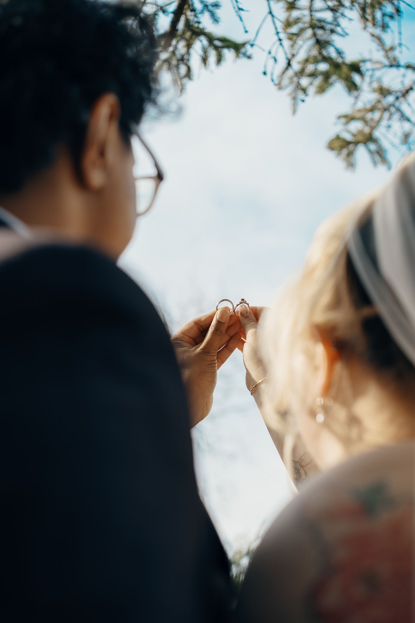 Bride and groom holding wedding rings beneath a tree in Scarborough, Ontario for intimate Toronto wedding photography.
