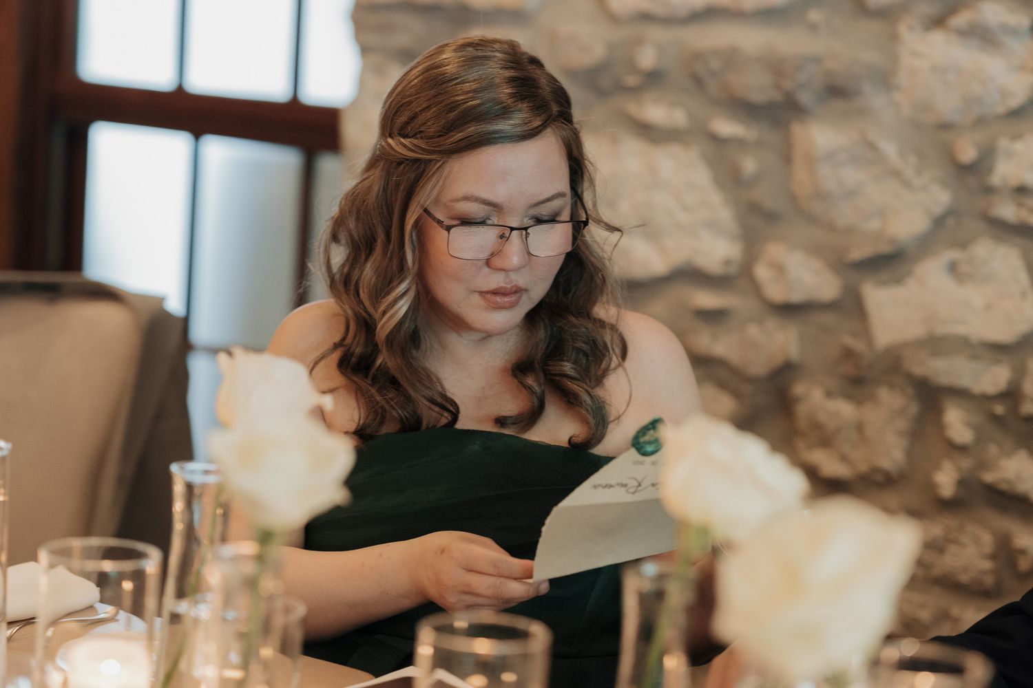 Woman in green dress reading a card at Cambridge Mill in Cambridge, Ontario during a candid wedding reception moment.