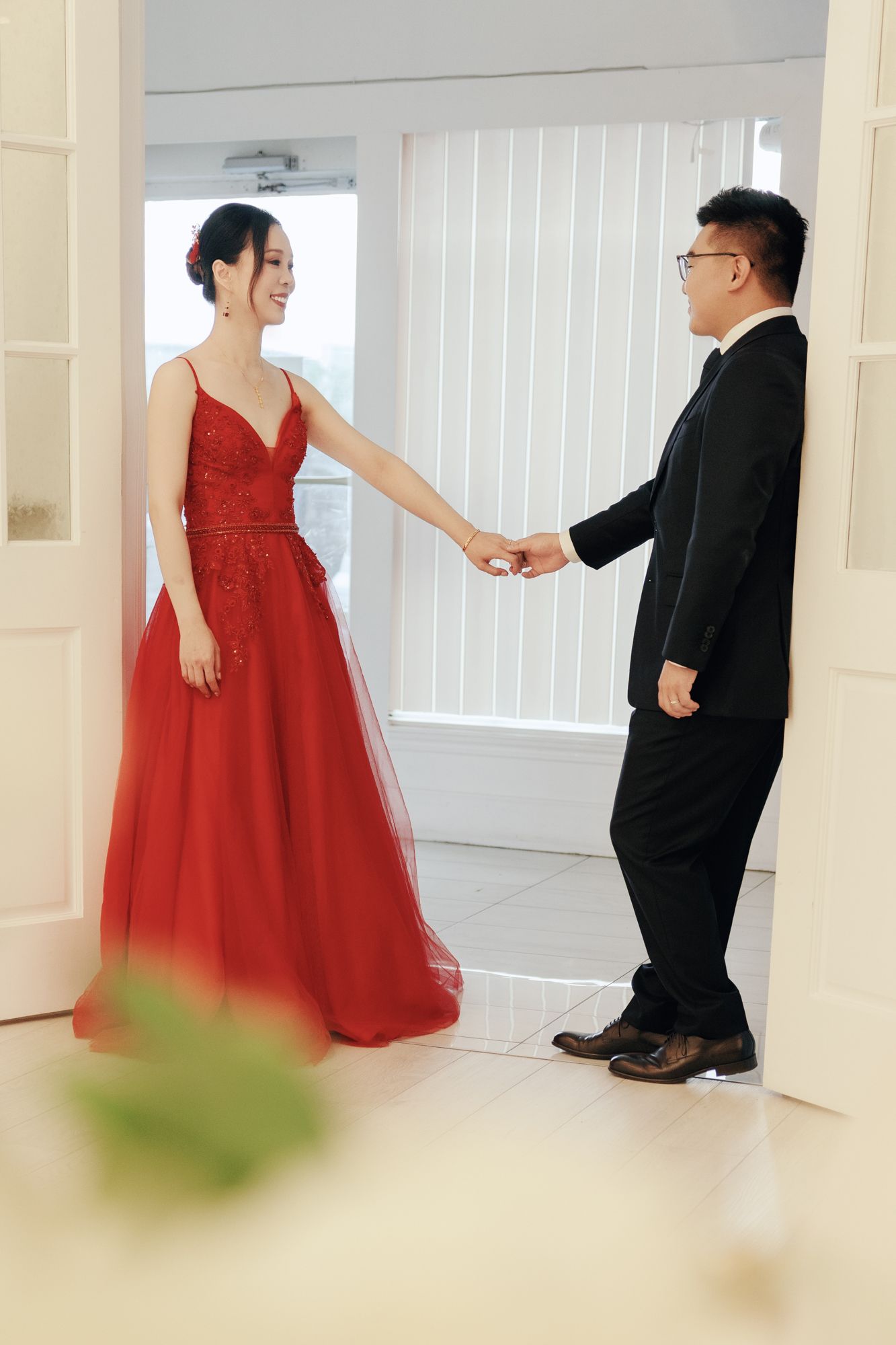 Smiling bride in red gown holding hands with groom in black suit at Bellamy Loft in North York, Toronto wedding portraits.