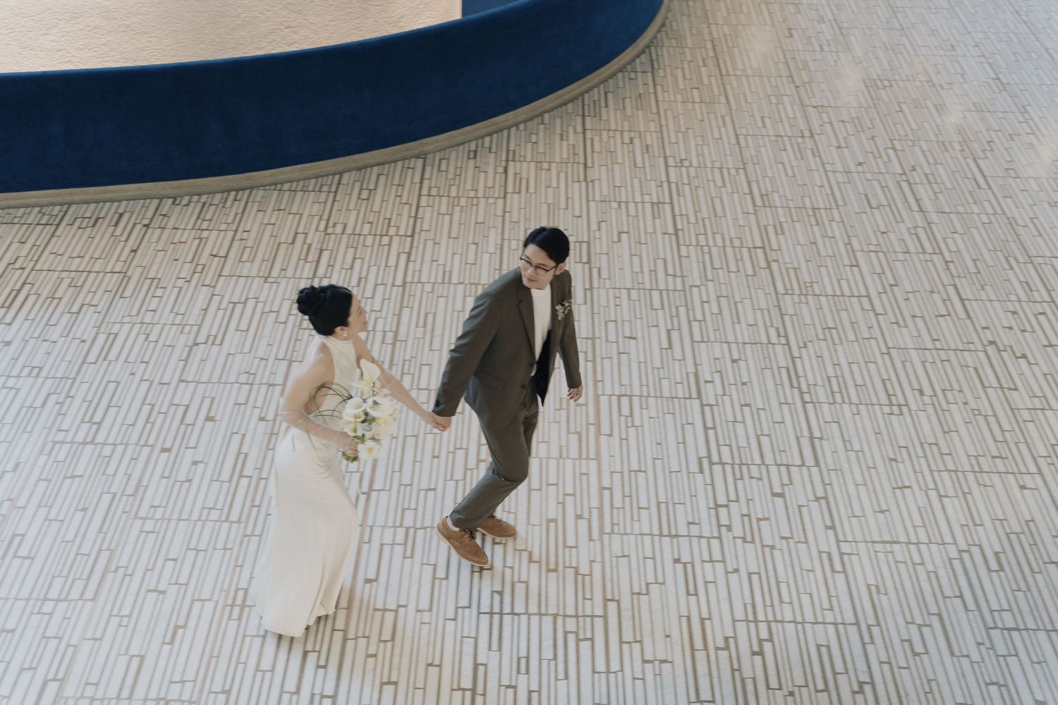 Bride and groom holding hands in Toronto City Hall courtyard for romantic overhead wedding photography.