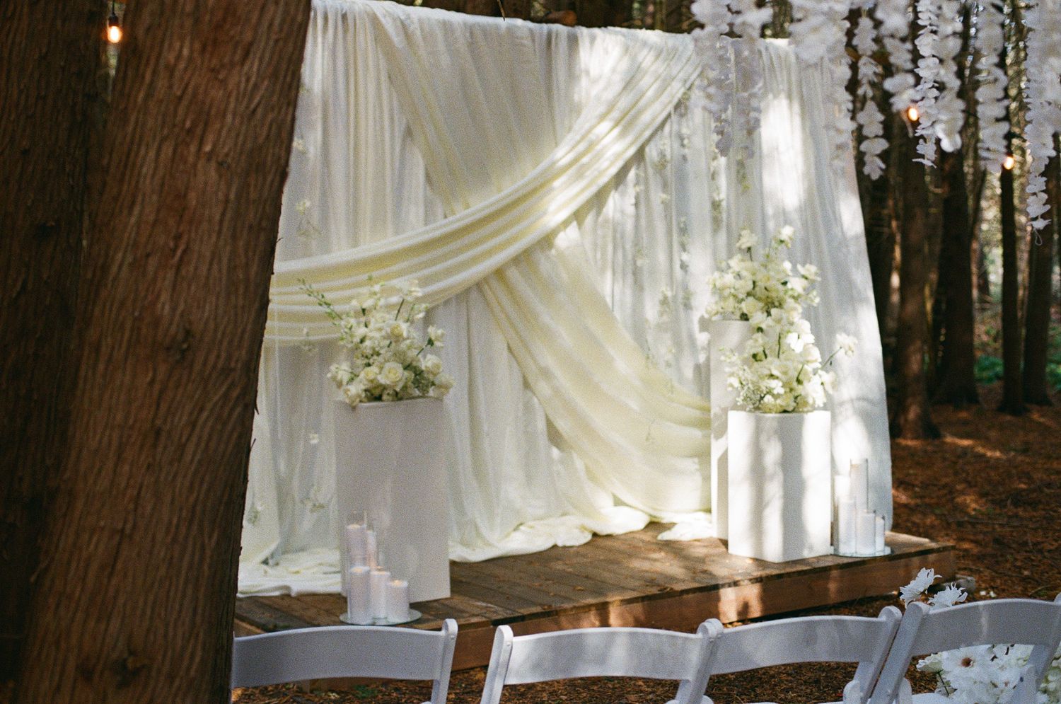 White draped ceremony setup with florals, wooden table, and chairs at Razi Estate in Schomberg for forest wedding photography.