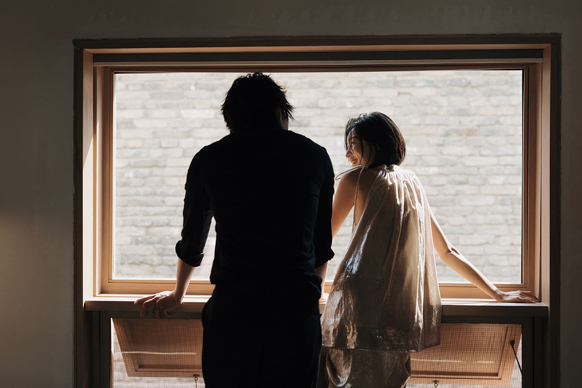 Couple getting ready together by a wooden-framed window before their Toronto wedding for candid documentary wedding photography