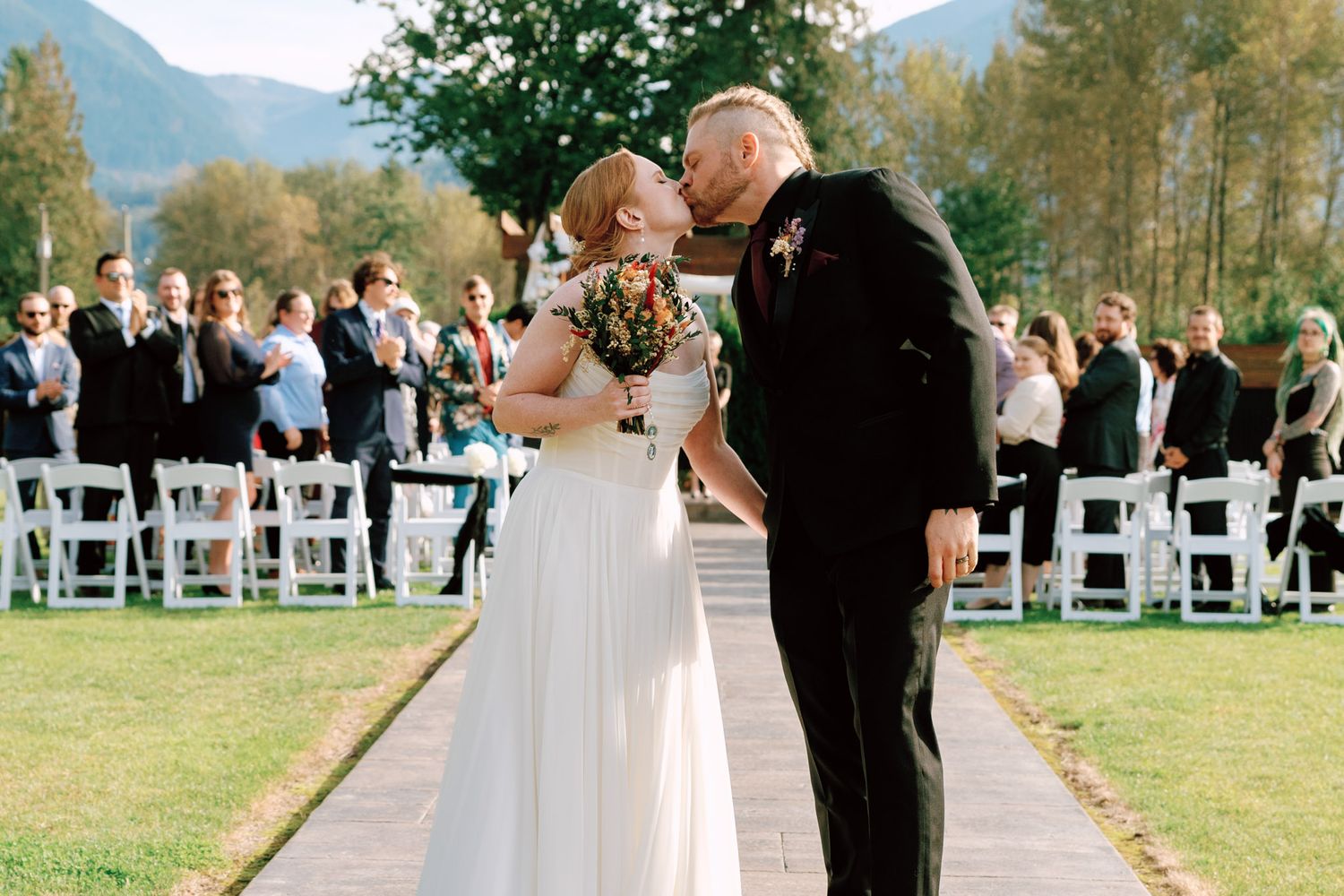 Bride and groom kissing after the ceremony aisle exit at Bridlewoods Event Center in Chilliwack, B.C. for Vancouver wedding photography