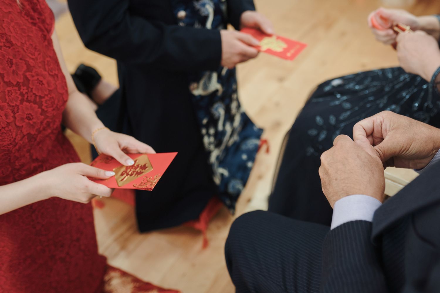 Hands exchanging red envelopes during a traditional Chinese tea ceremony in Toronto for cultural wedding photography.