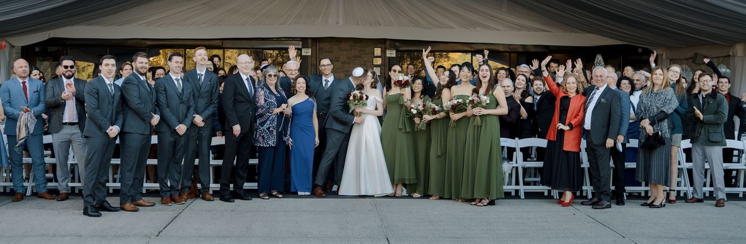 Bride, bridesmaids in green, and groomsmen posing under a tent at The Manor in King City for Toronto wedding photography
